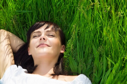 A young woman reclining in a grassy field after sedation dentistry in Fargo.